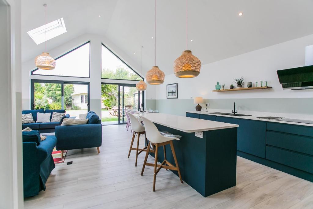 a kitchen and living room with blue and white cabinets at Saltwhistle - Bracklesham Bay in Chichester
