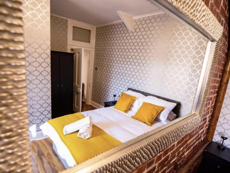 een slaapkamer met een groot bed met gele kussens bij Truro Central Studios in Truro