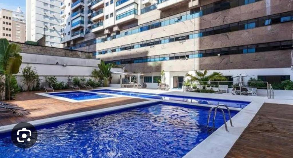une grande piscine en face d'un bâtiment dans l'établissement 6 Flats Capitania Varan, Pitangueiras, wifi, à Guarujá