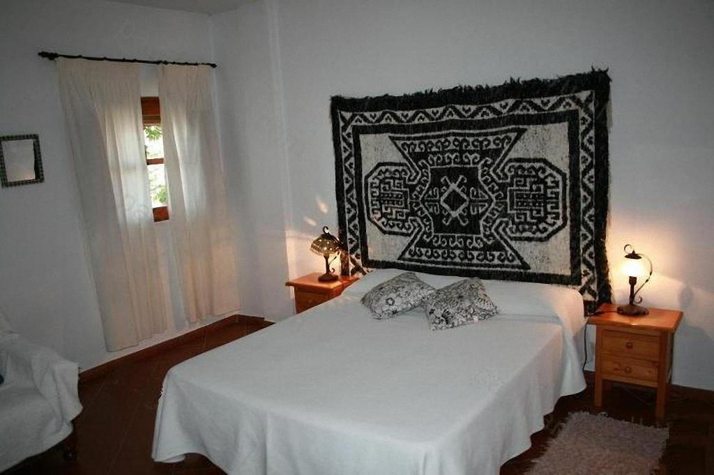 a bedroom with a bed with a black and white blanket at Casa De La Fuente in Bubión