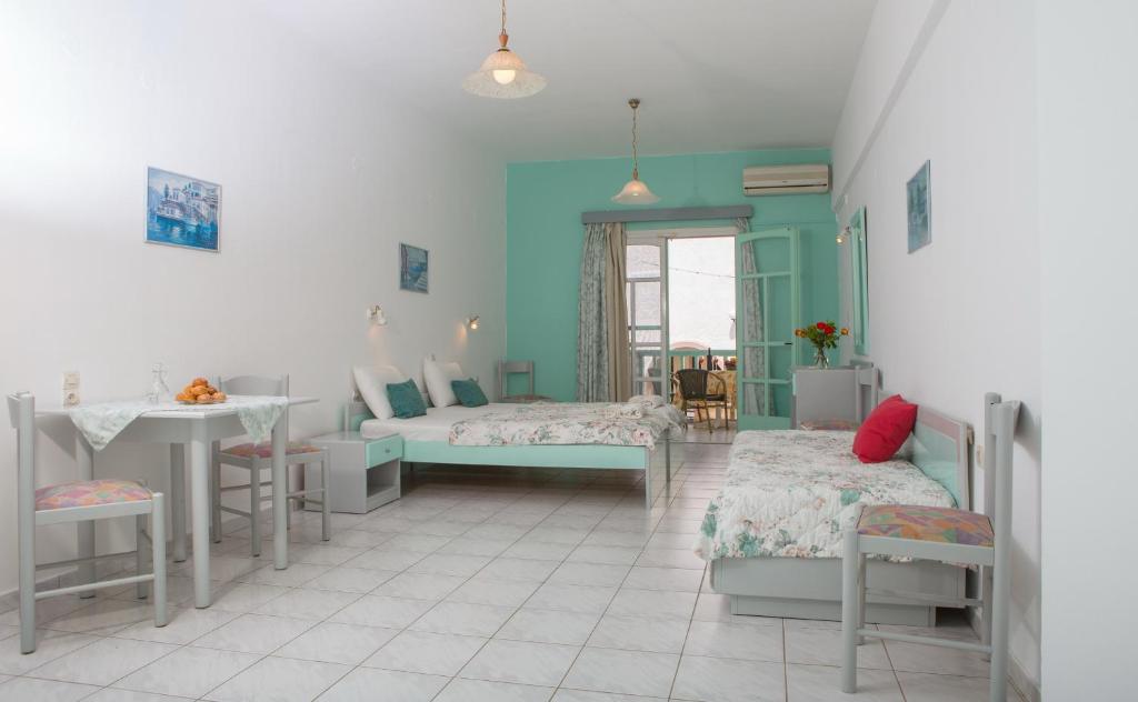 um quarto azul com duas camas e uma mesa e uma mesa em Mary's Studios em Agia Pelagia