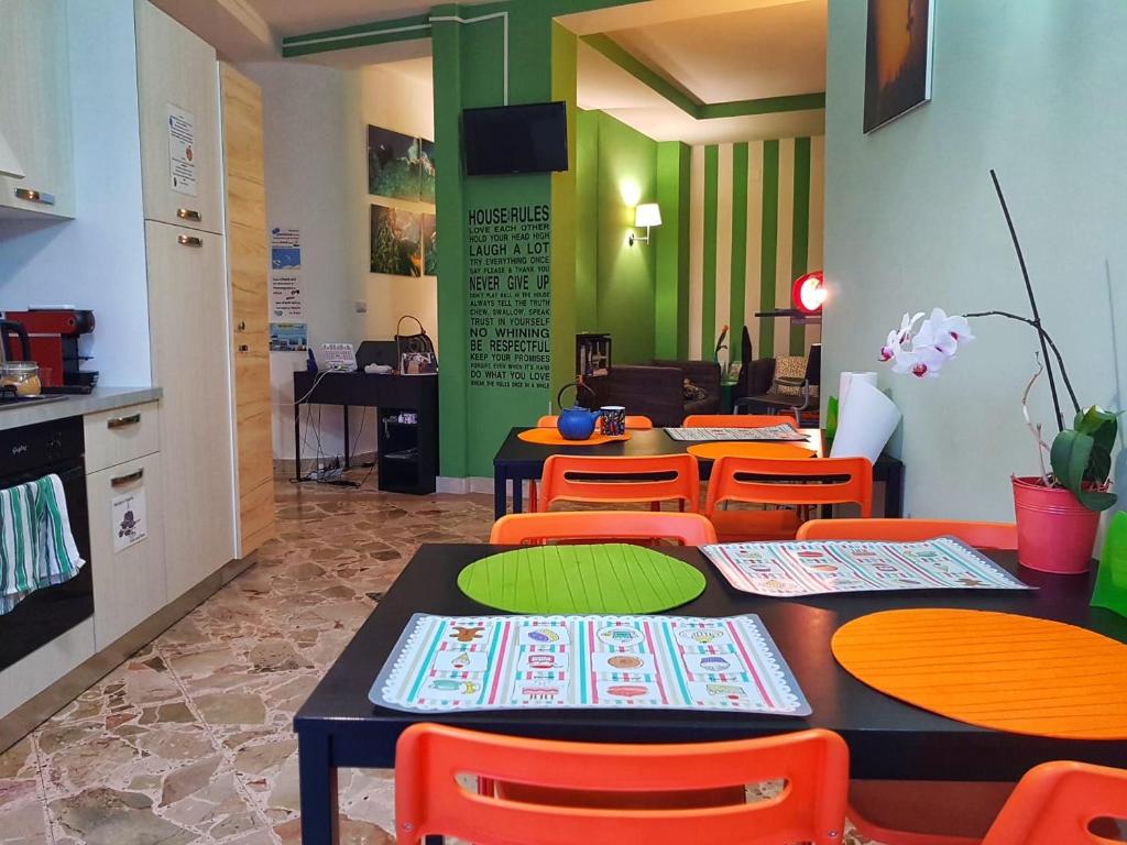 a restaurant with tables and orange chairs and green walls at Driade H in Milazzo