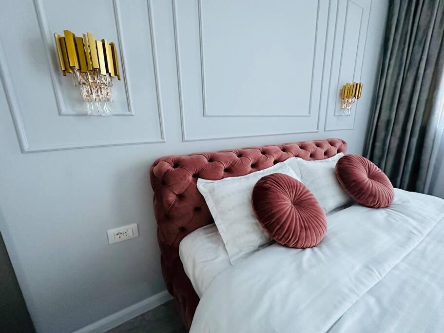 Una cama con dos almohadas rojas y blancas. en Premium Aparthotel La Mirada, en Mamaia Nord – Năvodari