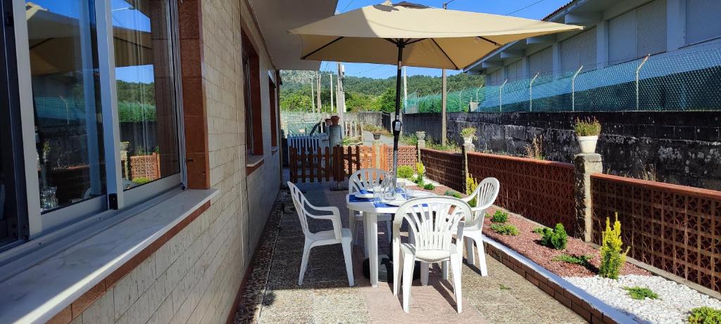 stół, krzesła i parasol na patio w obiekcie A Canexa w mieście Aldán