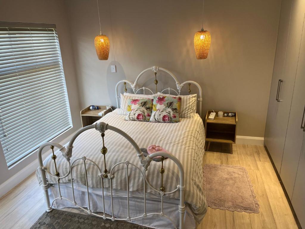um quarto com uma cama com uma colcha e almofadas brancas em Metanoia Kingswood Golf Estate em George