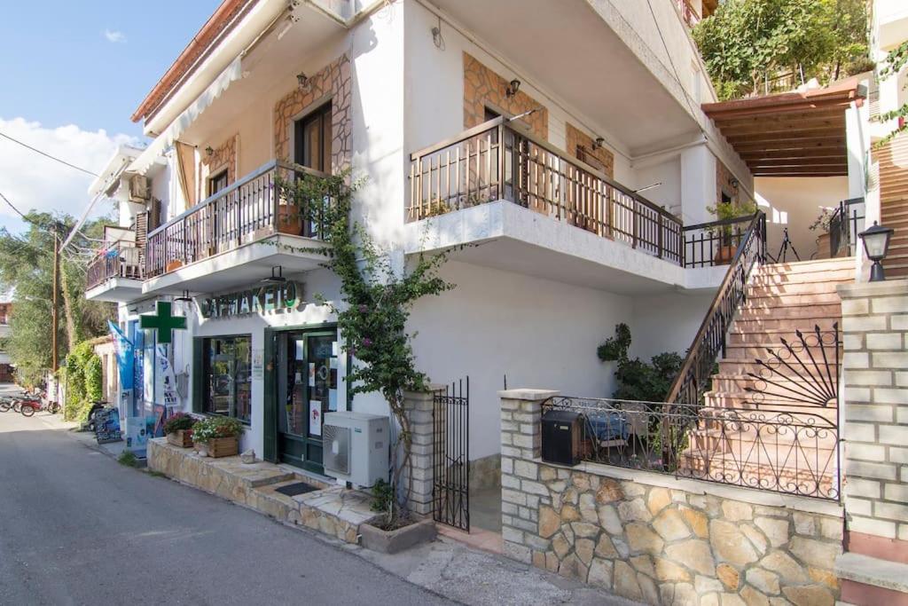 a white building with balconies on a street at Nikos apartment - Lakka Paxos in Lákka