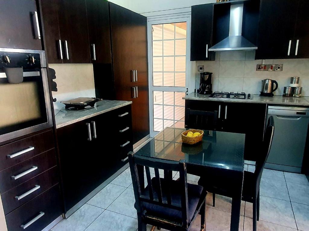 a kitchen with black cabinets and a black table and chairs at Trudy's home in Nicosia