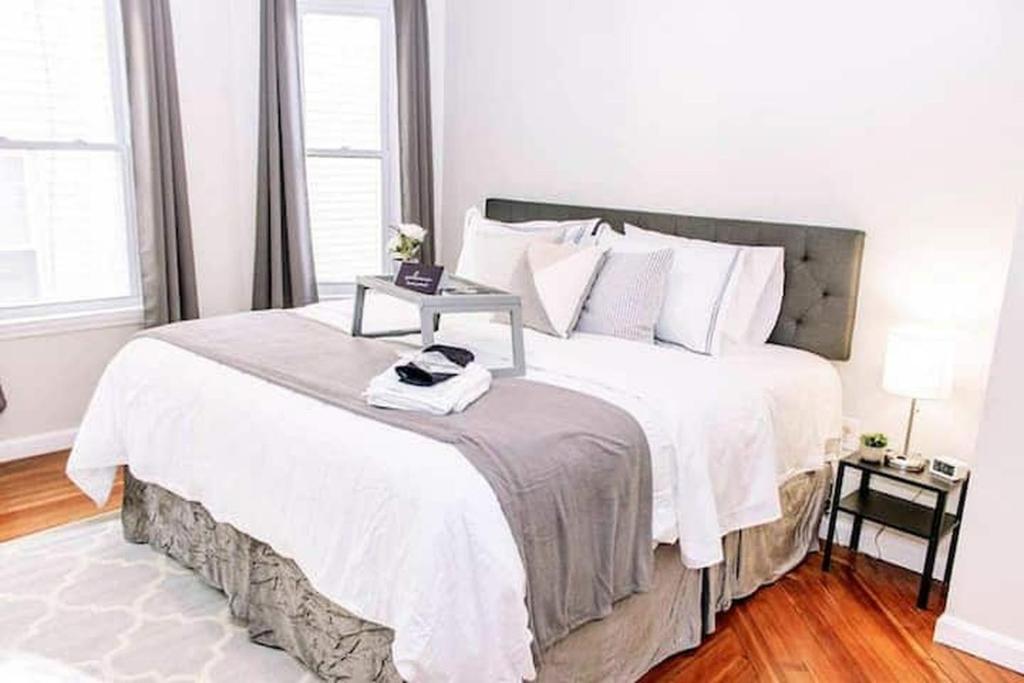 Un dormitorio con una gran cama blanca con una mesa. en 5BR triple decker apartment – 15 mins to City en Boston