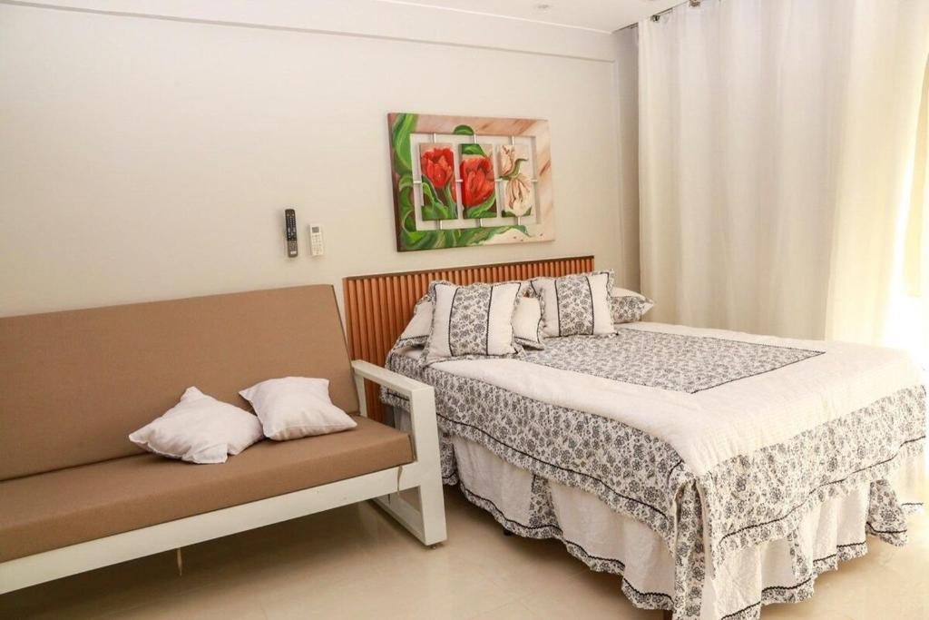 a bedroom with two beds and a bench in it at Apt Multishoping no centro do núcleo bandeirante in Núcleo Bandeirante