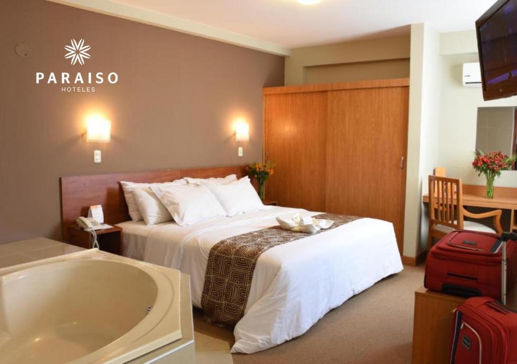 - une chambre d'hôtel avec un lit et une baignoire dans l'établissement Hoteles Paraiso TRUJILLO, à Trujillo