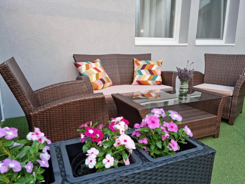 d'une terrasse avec des chaises en osier et des tables fleuries. dans l'établissement Center home Belvárosi kis lakás, csendes udvarral, à Esztergom