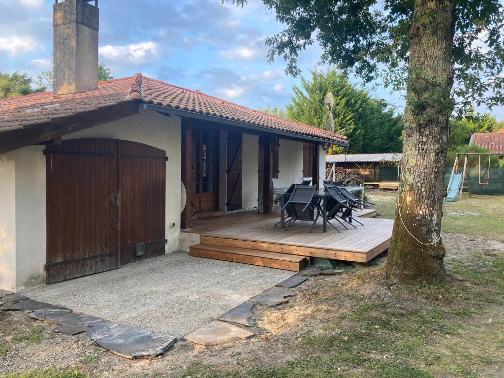 une maison avec une terrasse en bois à côté d'un arbre dans l'établissement maison moliets, à Moliets-et-Maa