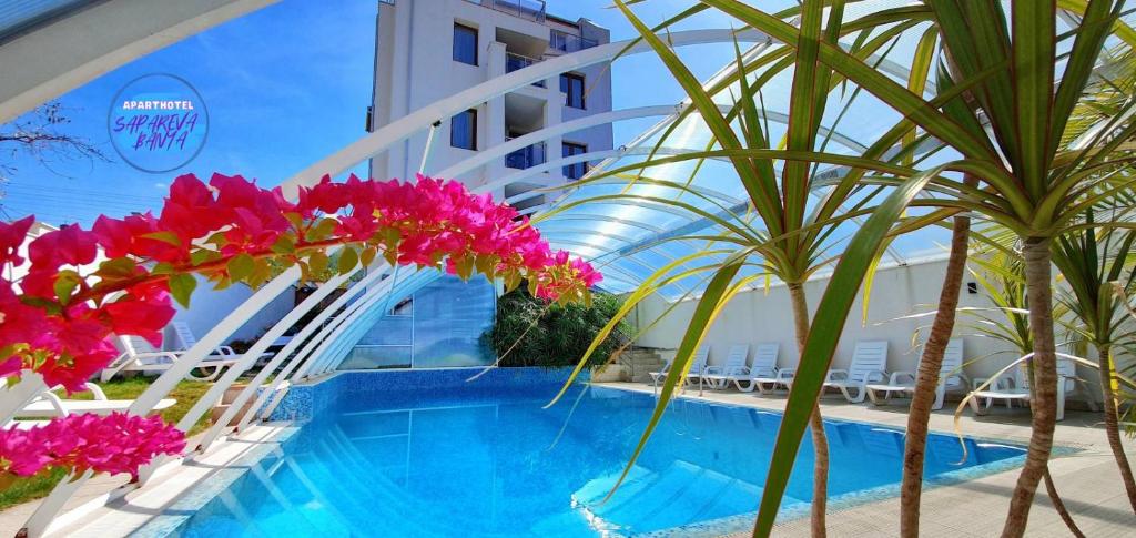 un complejo con piscina con flores rosas y palmeras en ENIS Hotel с минерален басейн, en Sapareva Banya