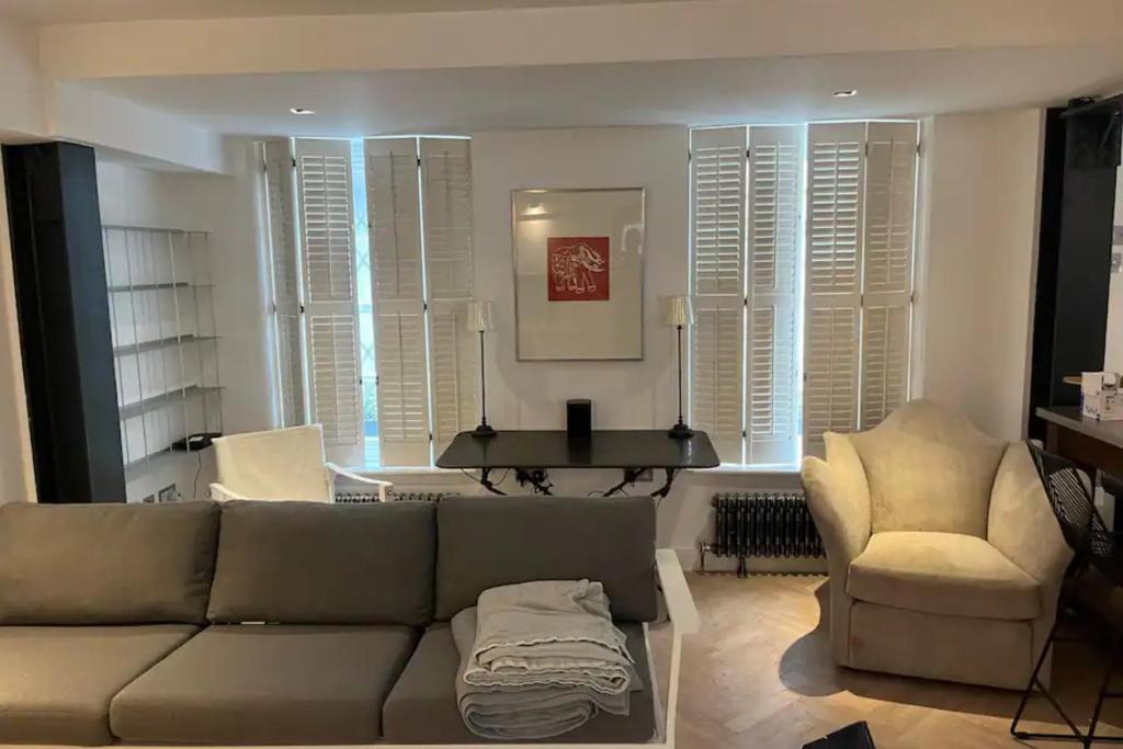 a living room with a couch and a chair and a piano at Sleek & Stylish 2BD Flat - Warren Street in London