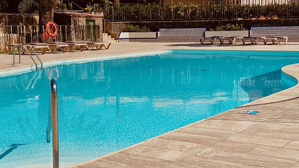 una gran piscina azul con sillas y mesas. en Click&Guest - Casa Queer, en Maspalomas