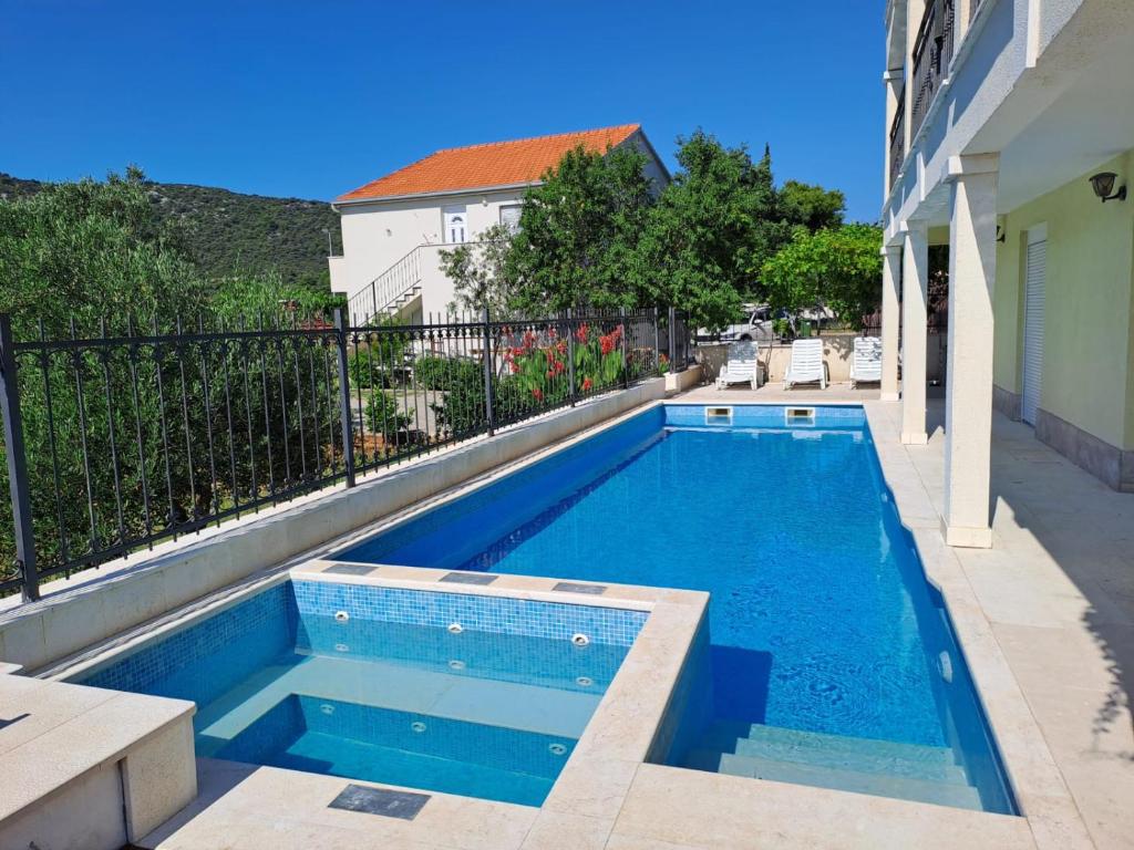 a swimming pool in a yard next to a building at Apartments Neli in Vinišće