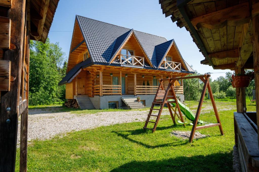 uma cabana de madeira com um baloiço e uma casa em Domki Burego w Białce Tatrzańskiej em Białka Tatrzanska