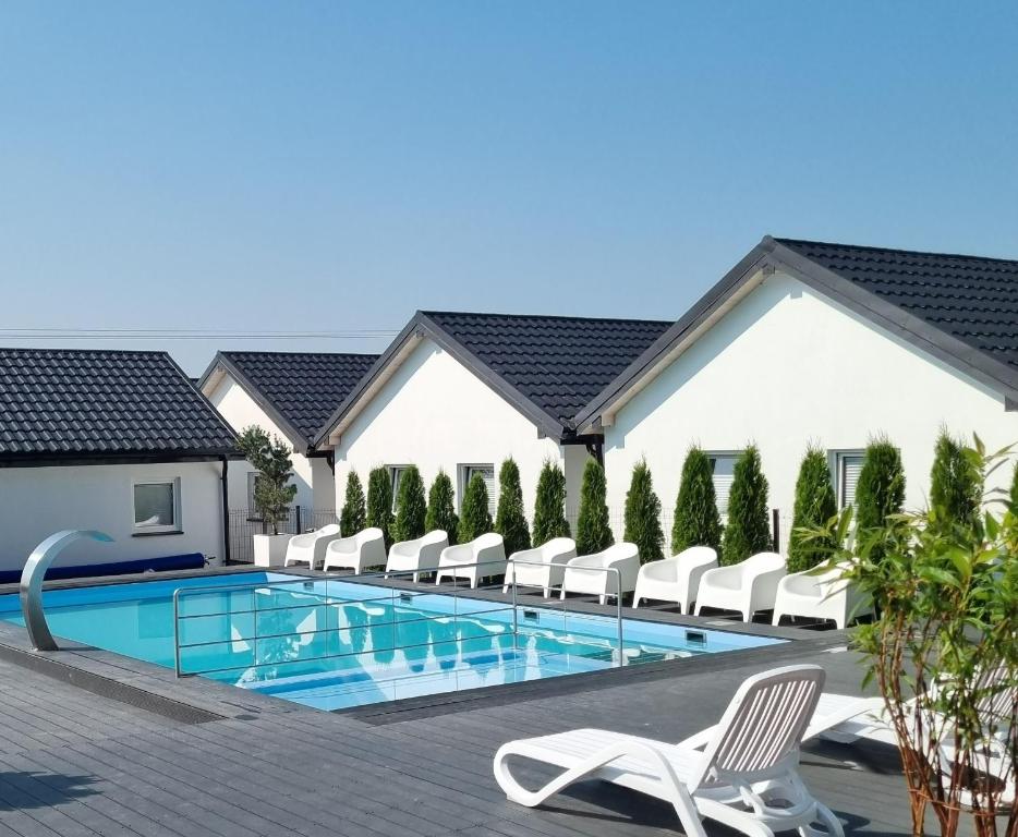 a swimming pool with lounge chairs and a resort at Nadmorska Przystan - Domki caloroczne in Ustka
