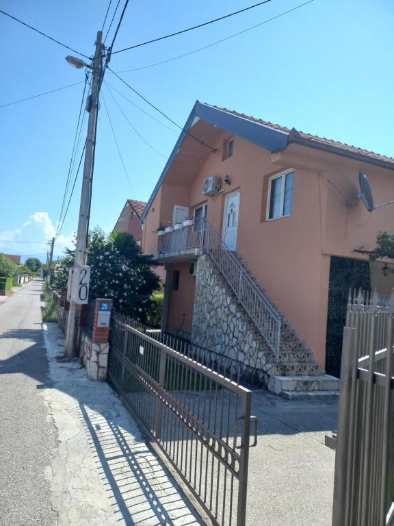 uma casa cor-de-rosa com uma vedação à frente. em Hostel Dragana em Podgorica