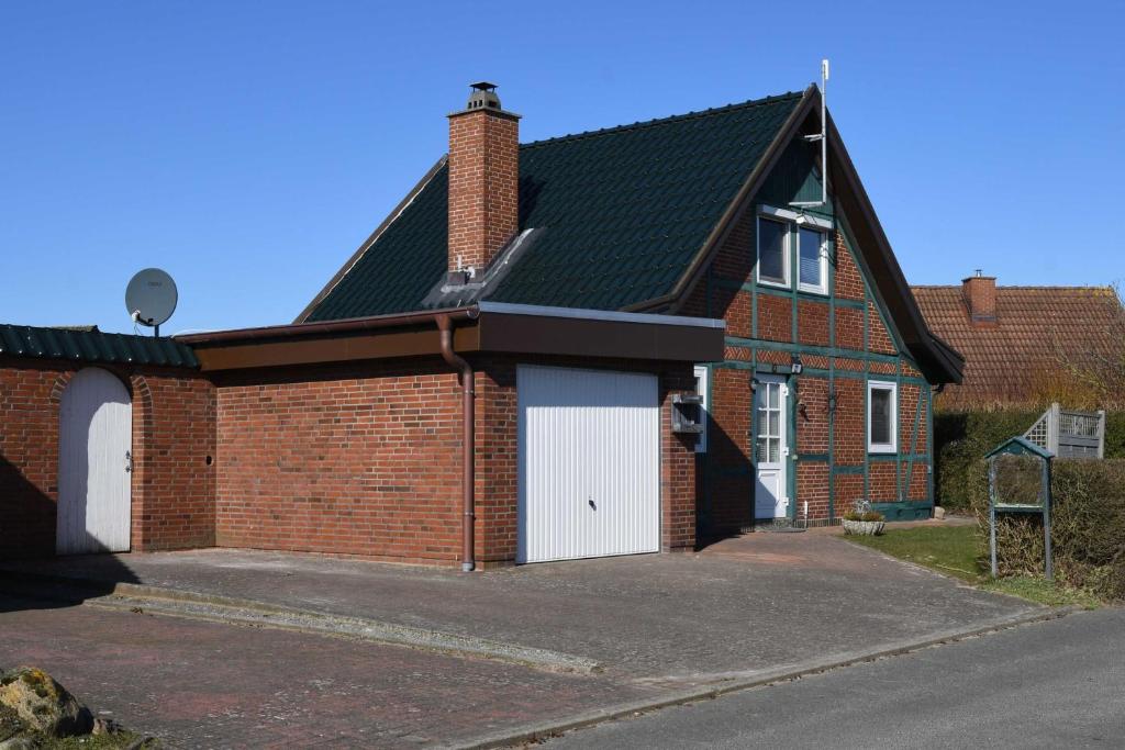 a red brick house with a white garage at FH Norderpiep 22 Sauna u Kamin in Friedrichskoog-Spitze