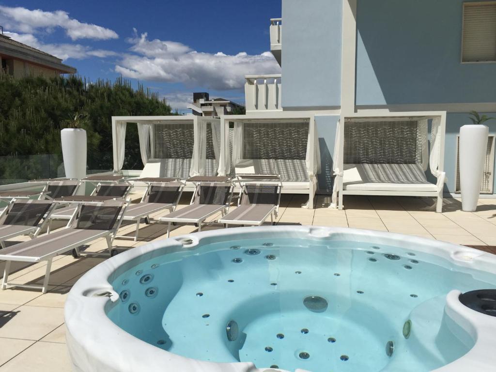a hot tub on a patio with lounge chairs at Hotel Montecarlo in Bibione