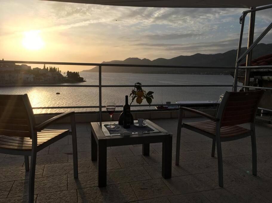 uma mesa e duas cadeiras e um copo de vinho na varanda em Korčula Sunset apartman em Korčula