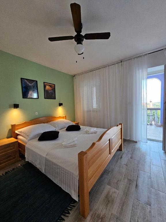 a bedroom with a large bed with a ceiling fan at Apartman Lila in Čunski