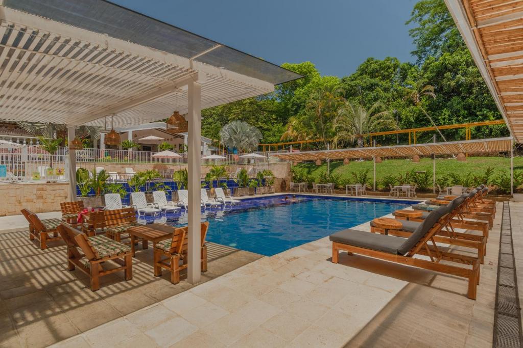 una piscina con sillas y un patio con mesa y sillón. en Hotel Villa Camila, en La Pintada