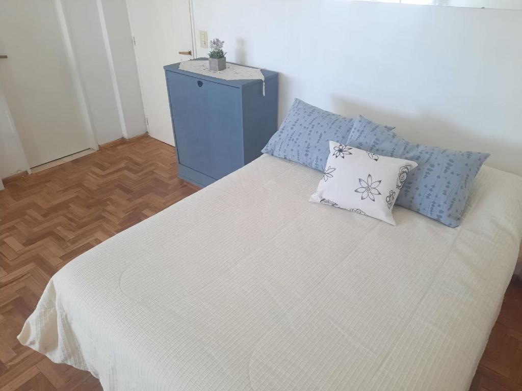 a white bed with two pillows and a blue cabinet at Mar de Anto in Puerto Madryn