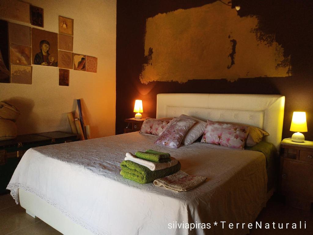 a bedroom with a bed with two lamps and two towels at B&B Fiadora Artist House in Decimoputzu