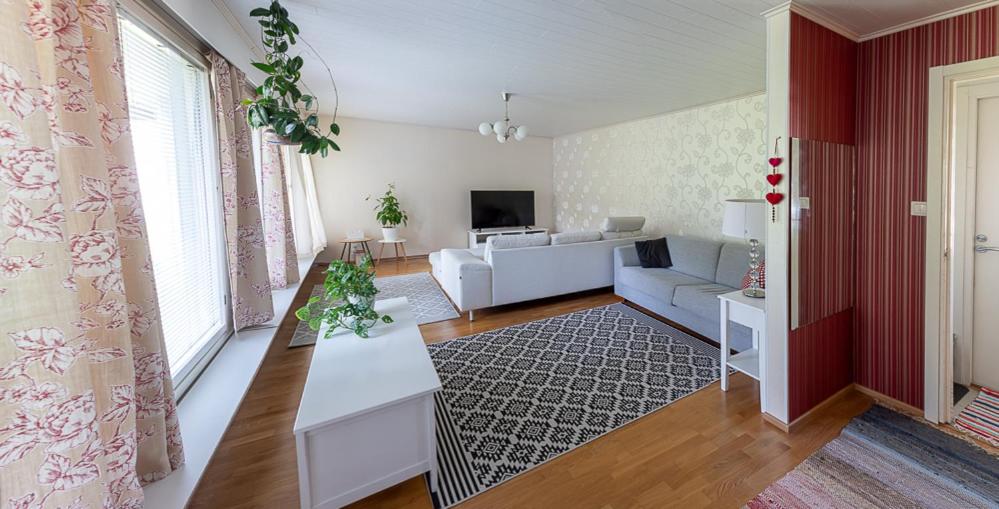 a living room with a white couch and a table at Omakotitalo keskustan lähellä in Joensuu