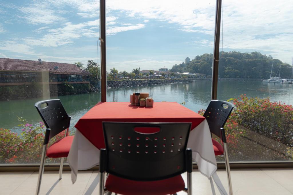 a red table and chairs with a view of a river at The Beach House in Panama City