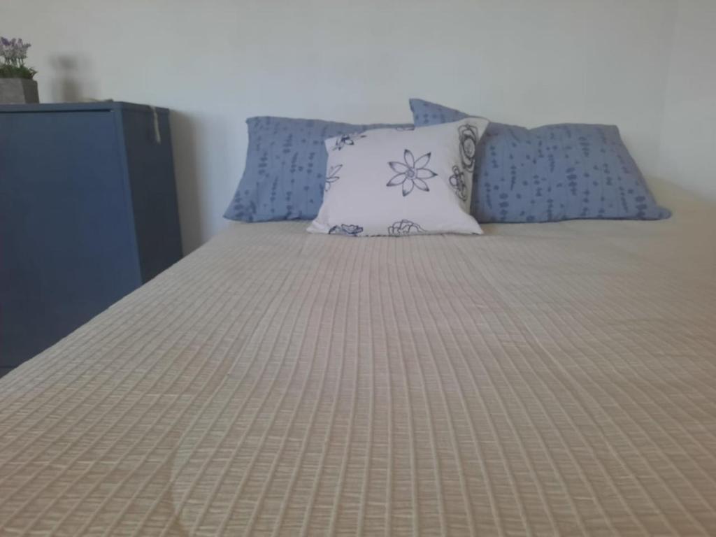 a bed with blue and white pillows on it at Mar de Anto in Puerto Madryn