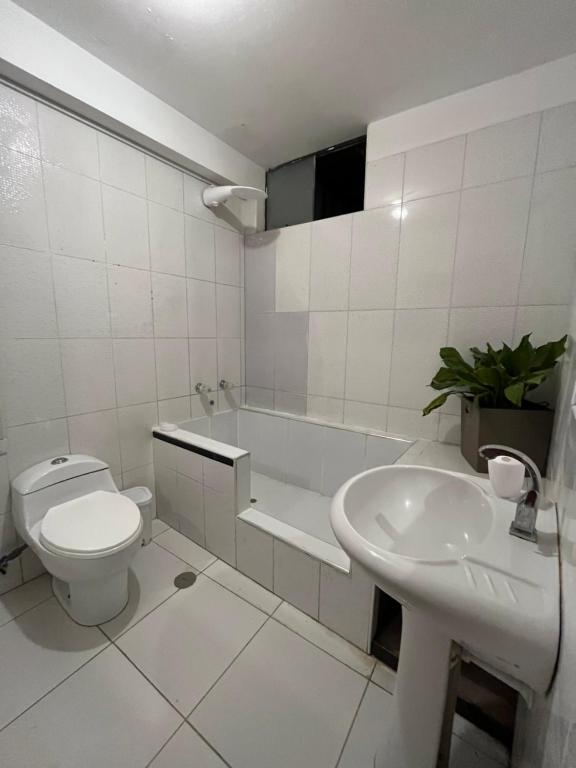 a white bathroom with a toilet and a sink at Castellares la Puebla Hostelería Departamento in Ayacucho