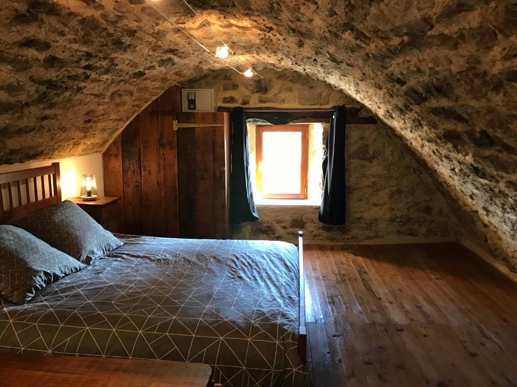 1 dormitorio con 1 cama en un edificio de piedra con ventana en Le grand gîte en Saint-Beauzély