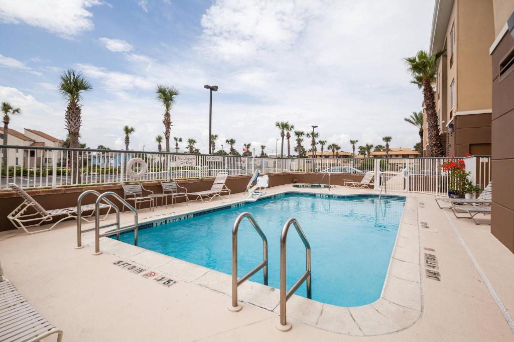 einen Pool in einem Resort mit Stühlen und Bäumen in der Unterkunft Fairfield Inn and Suites Jacksonville Beach in Jacksonville Beach