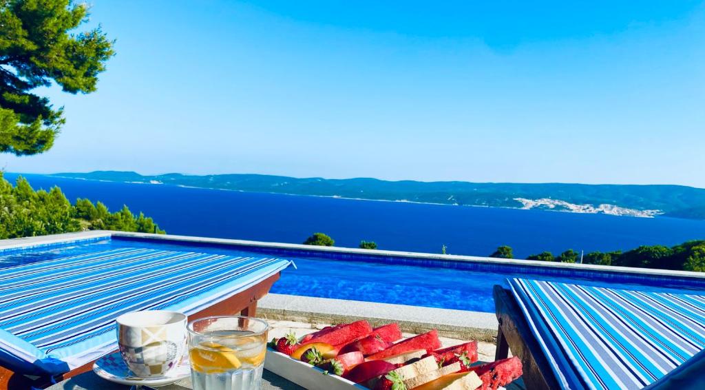 a tray of fruit on a table next to a swimming pool at Villa Jozini trudi in Lokva Rogoznica