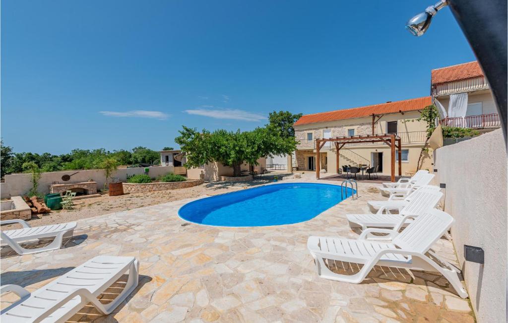 - une piscine avec des chaises longues à côté d'une maison dans l'établissement 3 Bedroom Stunning Home In Gornje Rastane, à Donje Raštane