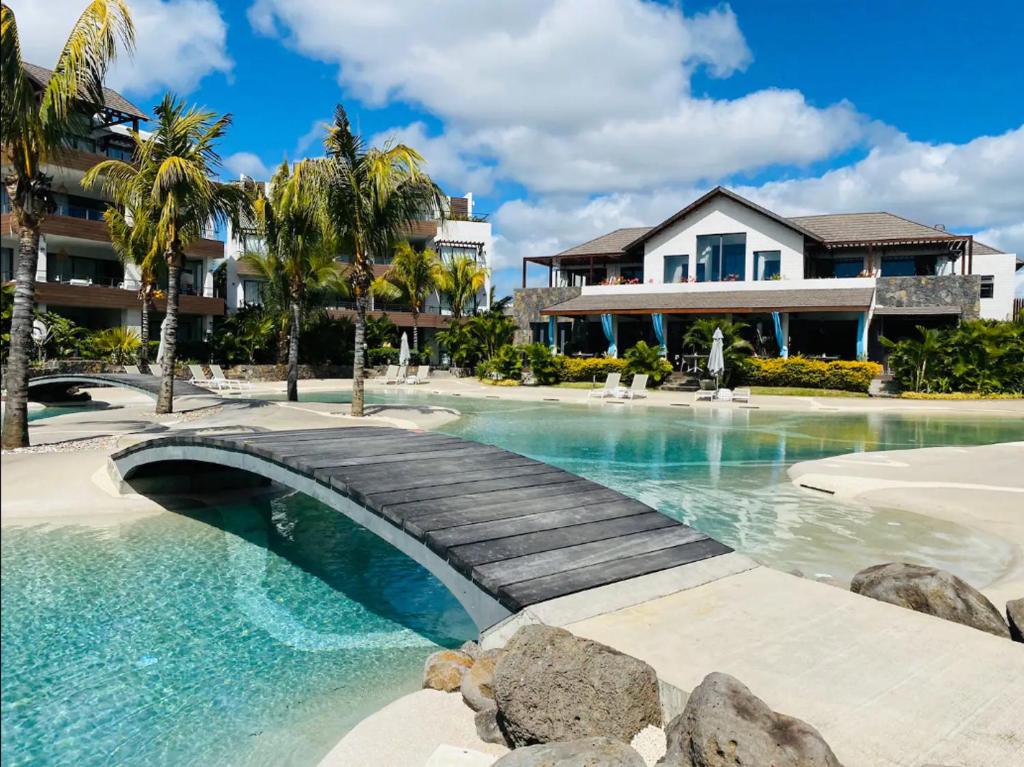 a swimming pool with a bridge in front of a house at Choisy Les Bains D2 in Mont Choisy