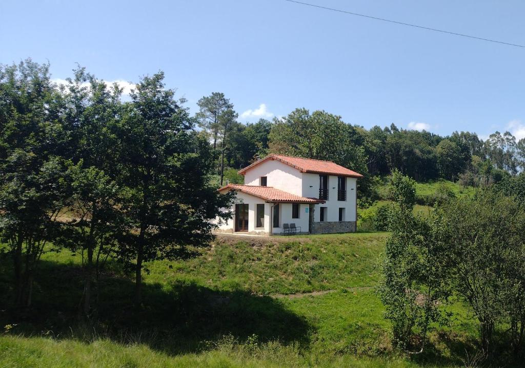 een klein wit huis op een heuvel in een veld bij Casa Rural Tulia in Grado