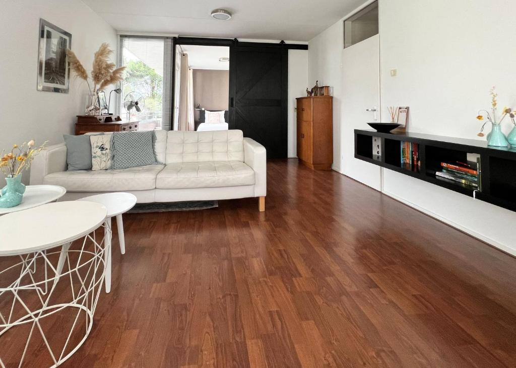 uma sala de estar com um sofá branco e pisos em madeira em Center Appartement Apeldoorn em Apeldoorn