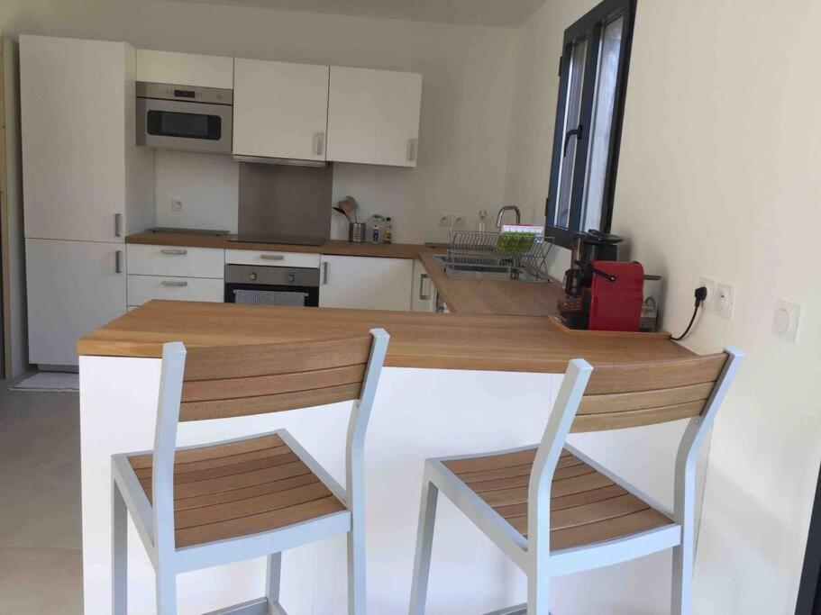 cocina con mesa de madera y 2 sillas en Villa callinajo 1 T3 , 6 places Clim à 1 min de la plage, en Belgodère