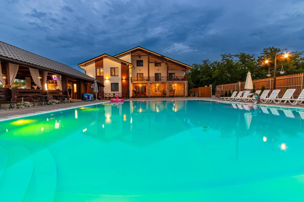 a large swimming pool with chairs in front of a house at Sofion hotel&resort in Solotvyno