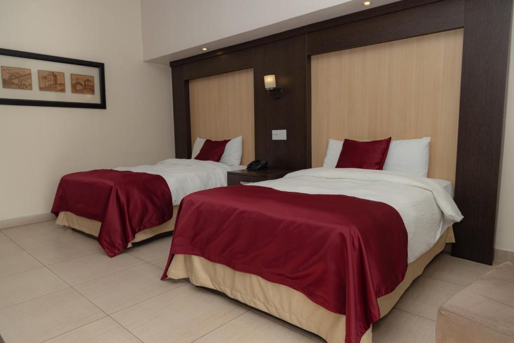 two beds in a hotel room with red and white sheets at The Beach House in Panama City