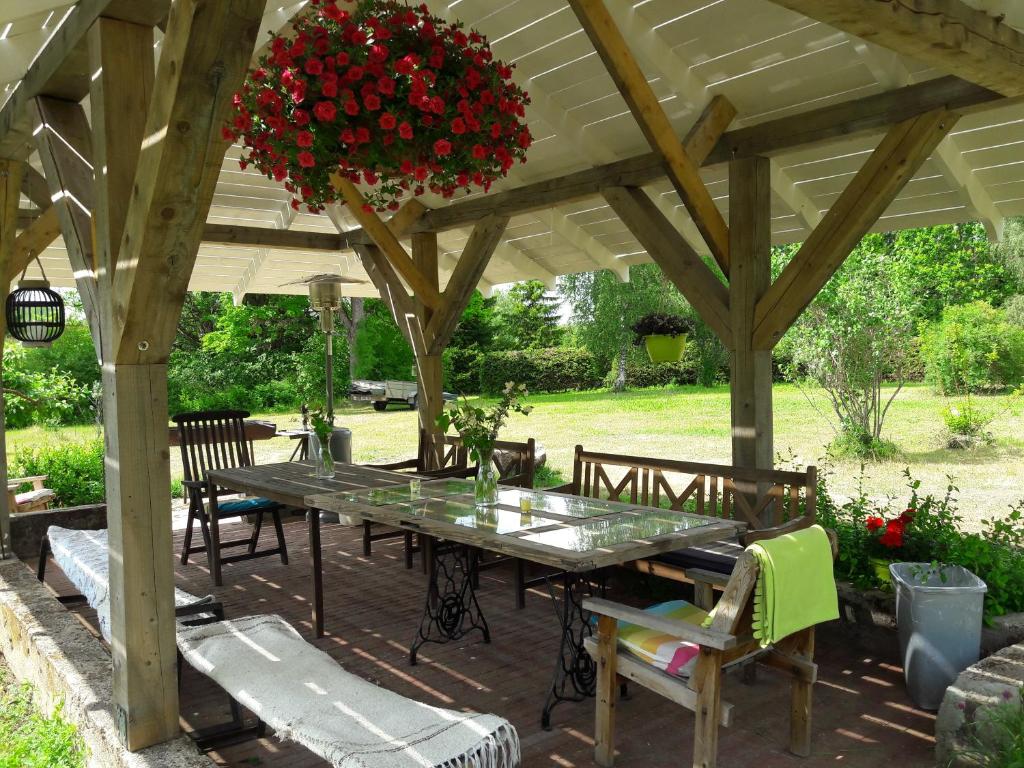 a table and chairs under a wooden pergola at Järve Talu Puhkemaja in Otepää