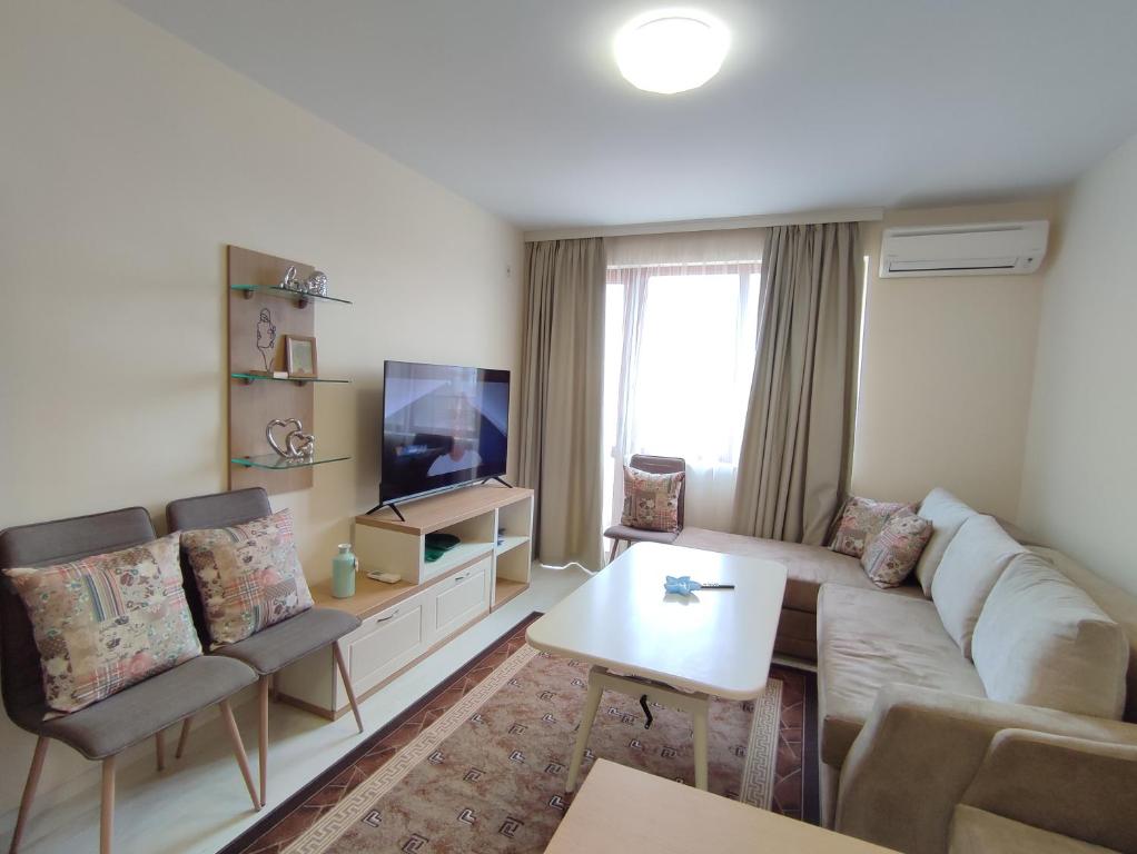 a living room with a couch and a tv at Кай Apartment's Sarafovo in Burgas