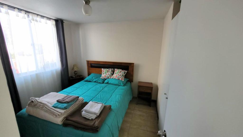 Un dormitorio con una cama con sábanas verdes y una ventana en Departamento a pasos del borde costero en condominio privado, en La Serena