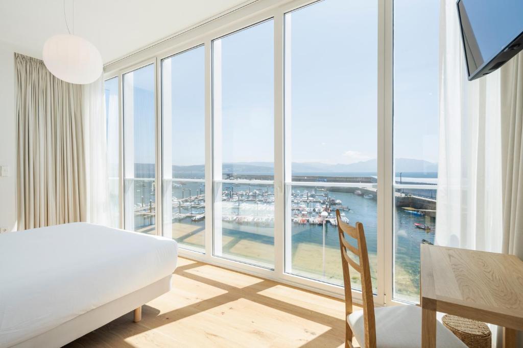 ein Schlafzimmer mit einem Bett und einem großen Fenster in der Unterkunft Porto Real Hotel in Kap Finisterre