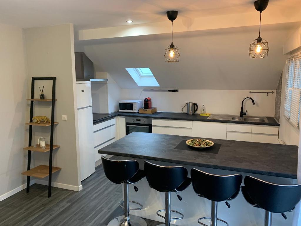 a kitchen with a black counter top and some chairs at Appartement L'épicentre 2 in Scionzier