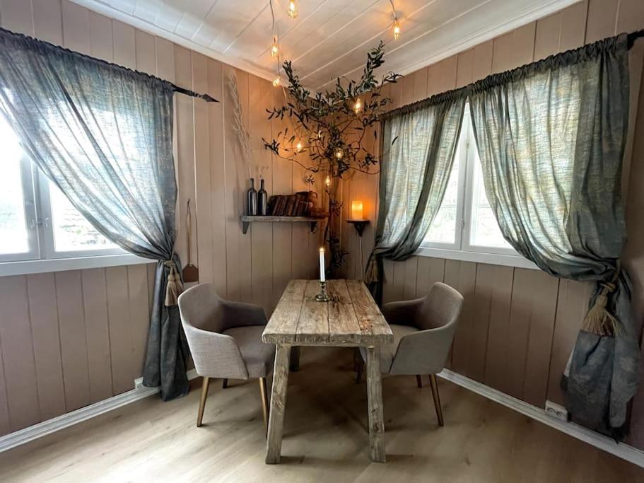 a table and chairs in a room with windows at Hadeland Cottage in Lunner